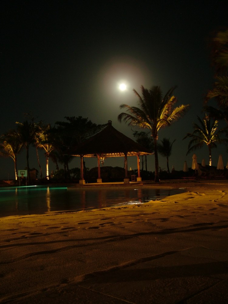 Mond hinter Hochnebel über Poollandschaft in Bali