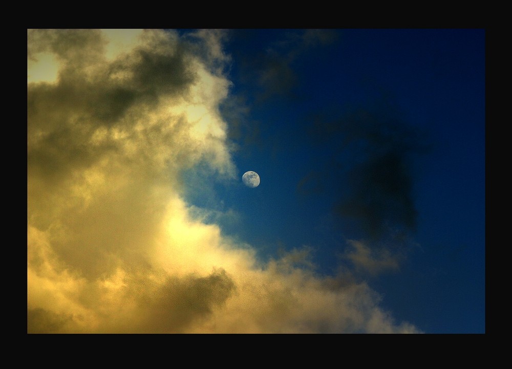 Mond in den Wolken von der Sonne belichtet.