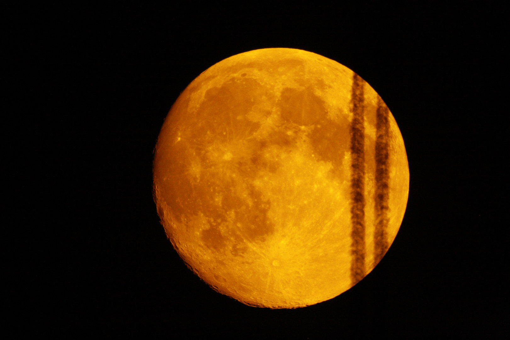 Mond mit Flugzeugschweif eines durchfliegenden Jets