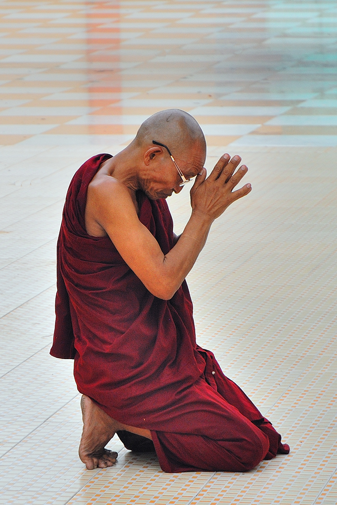 Monk praying to the Buddha in Botataung Pagoda in Rangoon