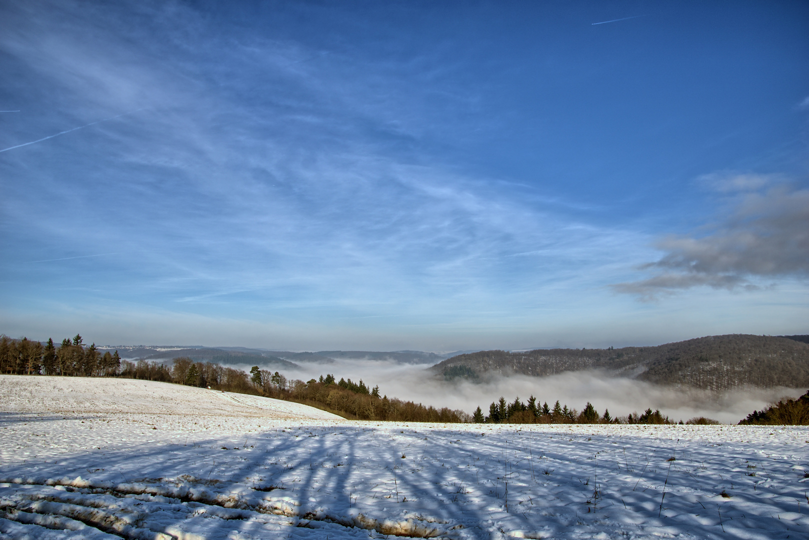 Nebel füllt das Tal einer Winterlandschaft