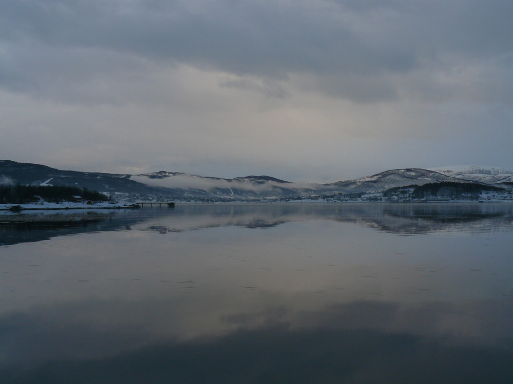 Nebelschwaden am Abend ueber dem Fjord
