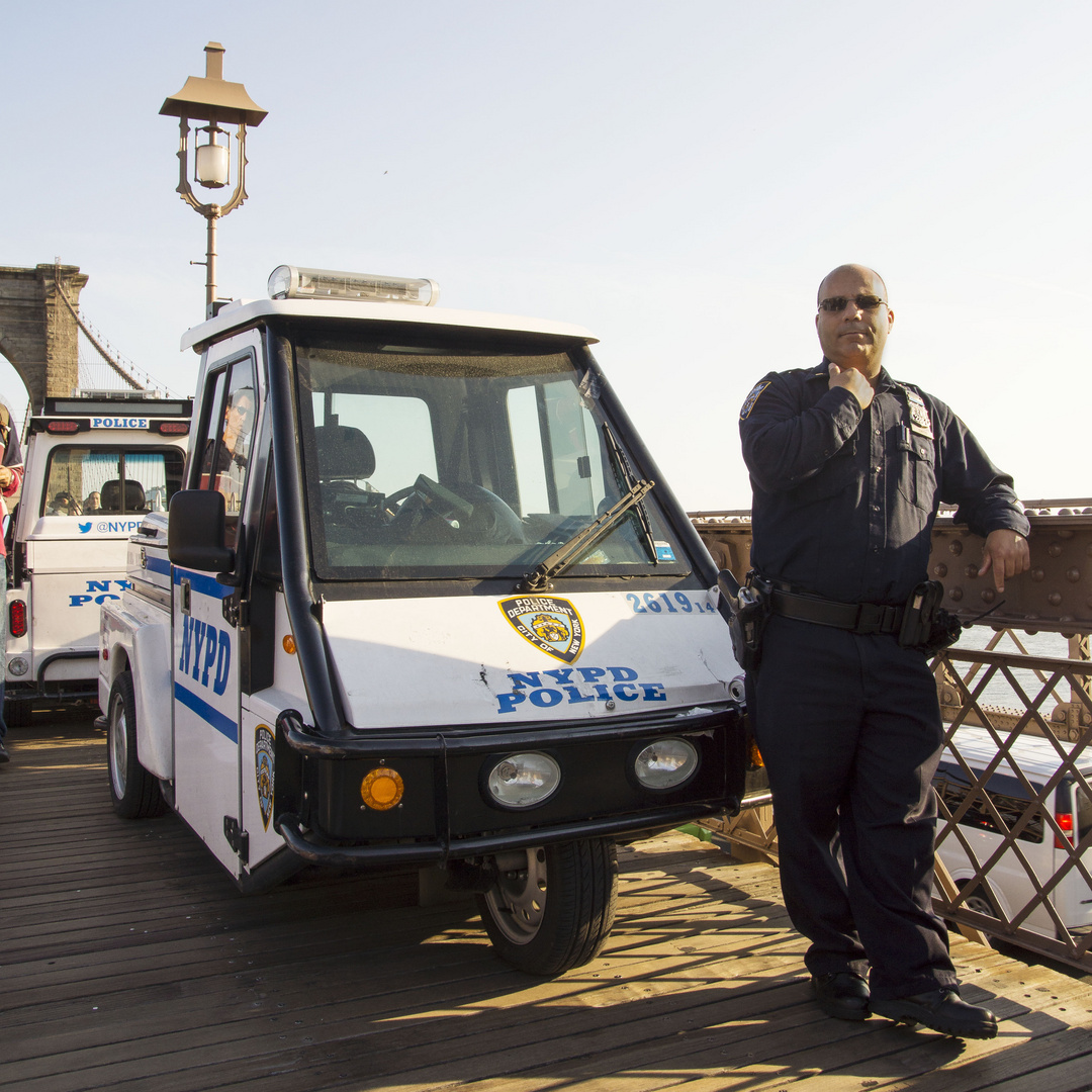 New Yorker Polizist mit Dienstfahrzeug auf der Brooklynbridge
