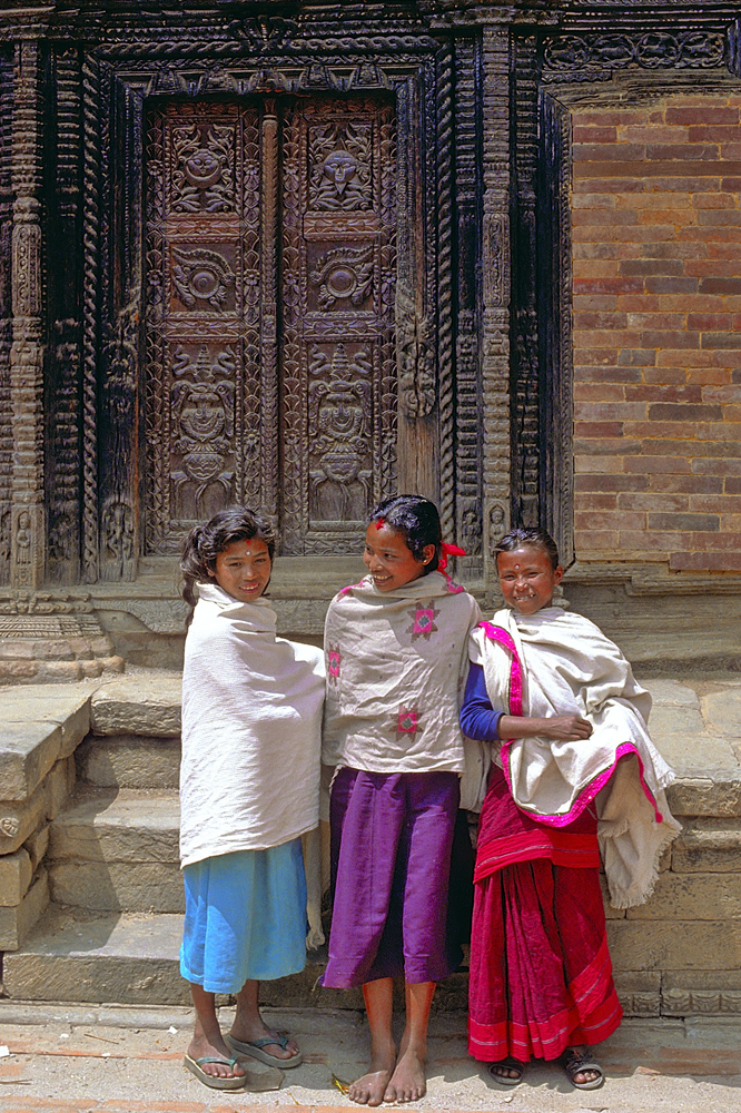 Newa girls in front of a carved gate in Bhaktapur