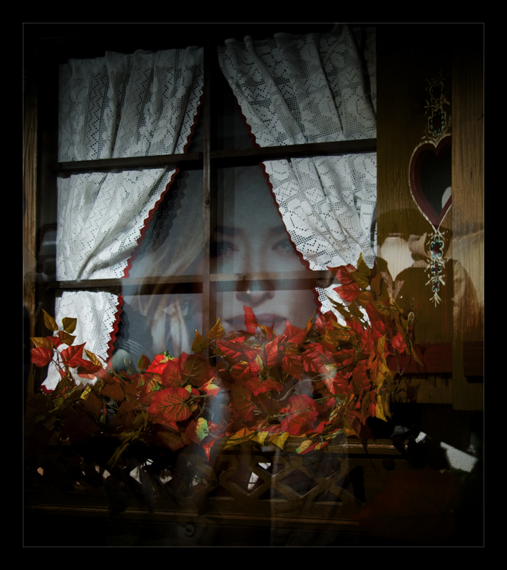 Occhi di una donna ritratta in un manifesto che si riflette nei vetri di una finestra in una vetrina
