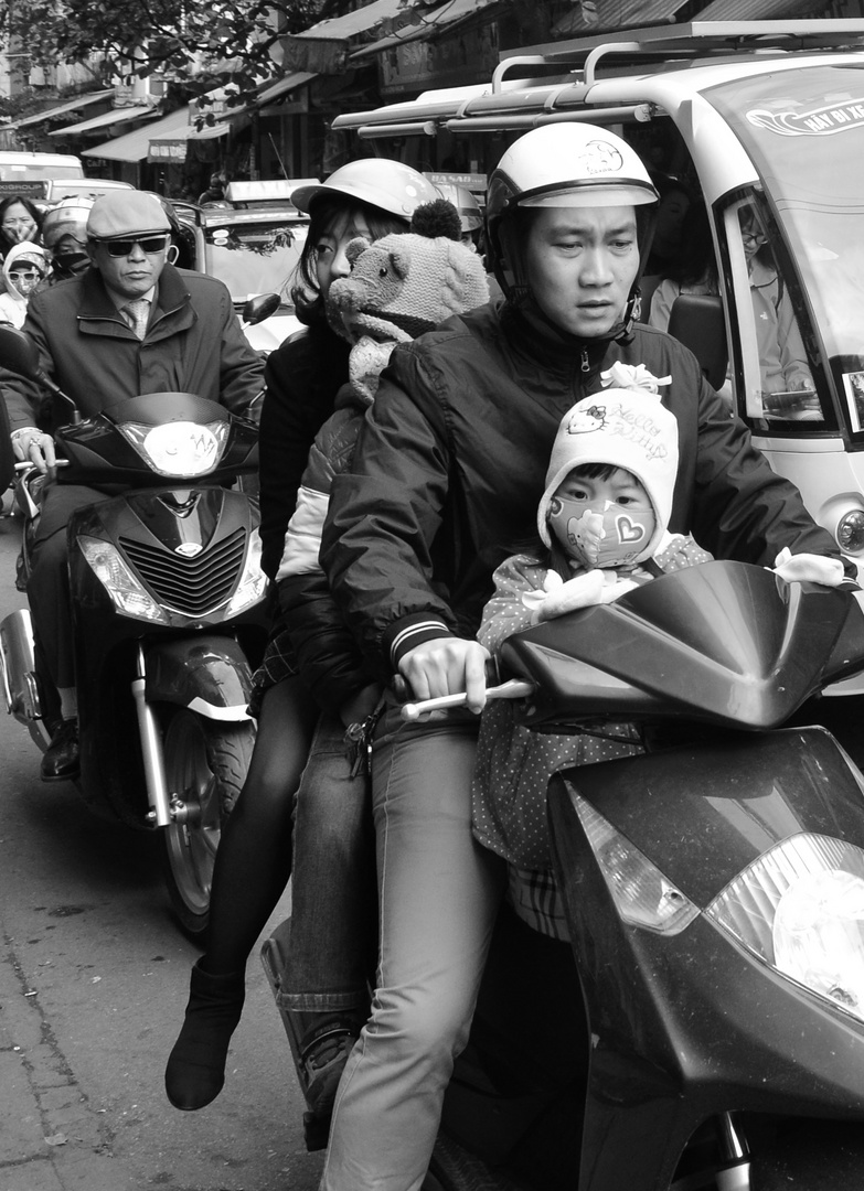 One scooter serves a family of four - in the streets of Hanoi.