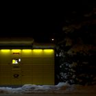 Packstation in verschneiter Mittelstadt bei Dunkelheit