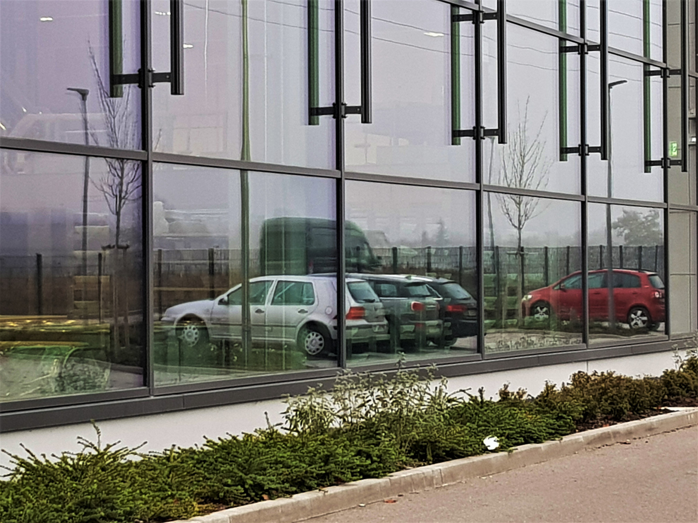         Parkplatzspiegelung in einer Fensterfassade