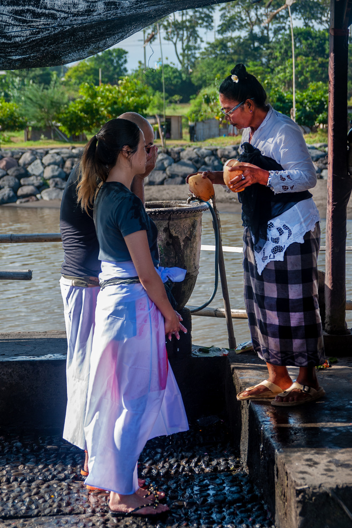 Pemangku priest spalshes holy water