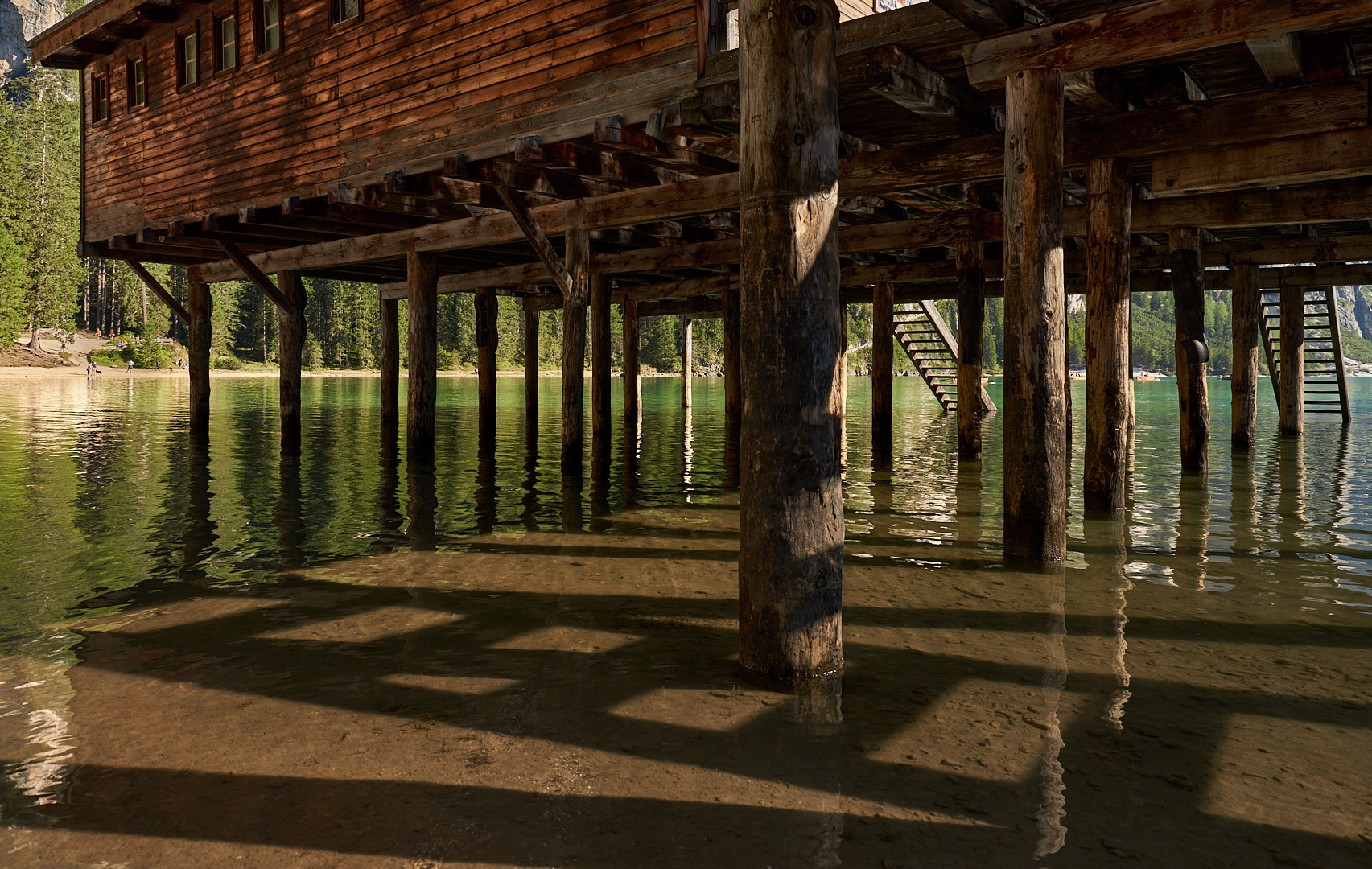 Pfostenspiegelungen und Schattenwürfe unter dem Bootshaus am Pragser Wildsee.