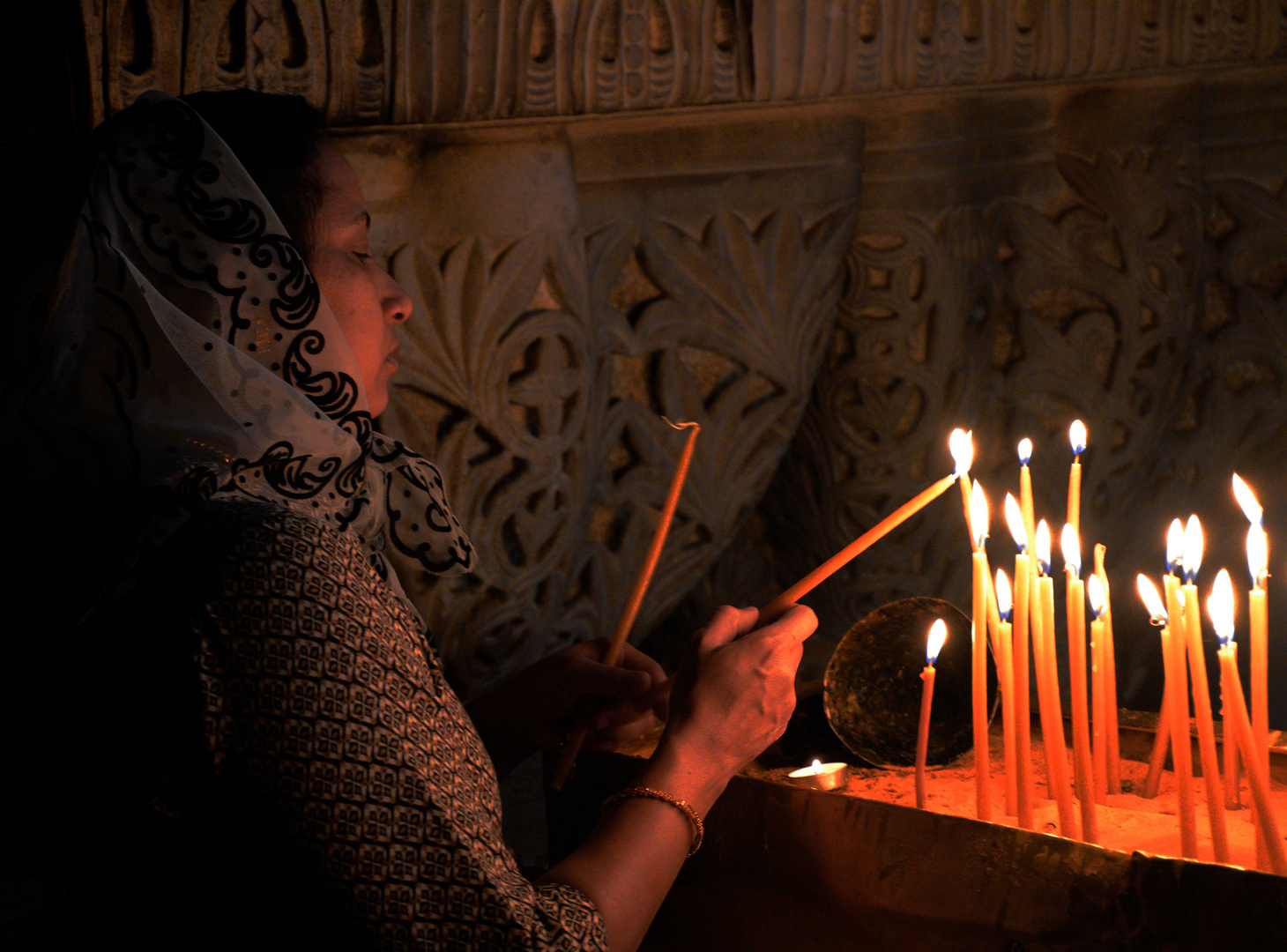 Pilgerin beim Anzünden von Kerzen nahe des Kreuzigungsortes Jesu