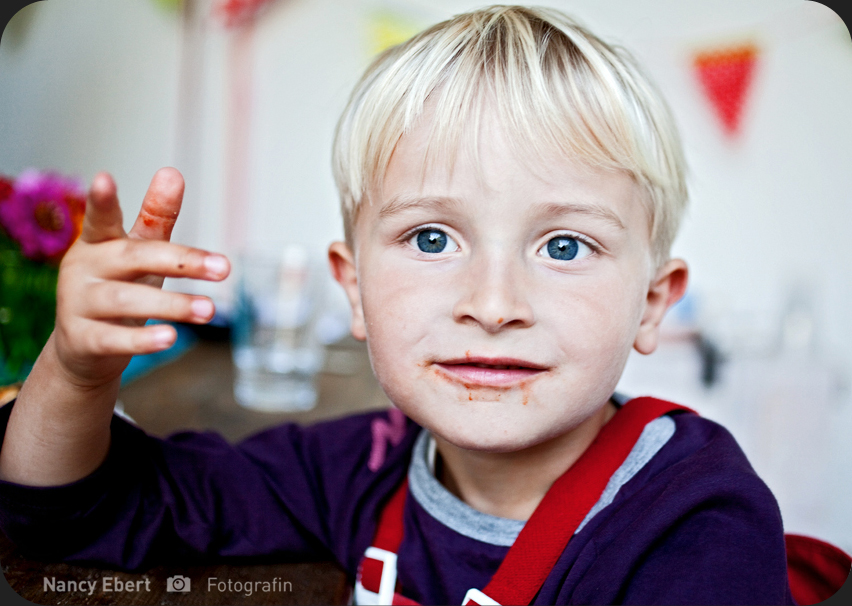 Portrait von blondem Jungen mit Tomatensoße