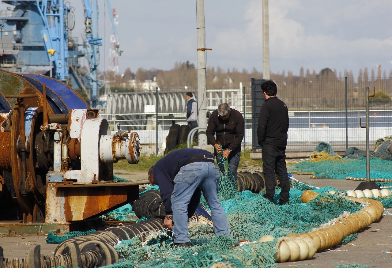 Quelques ouvriers réparant les filets de pêche.