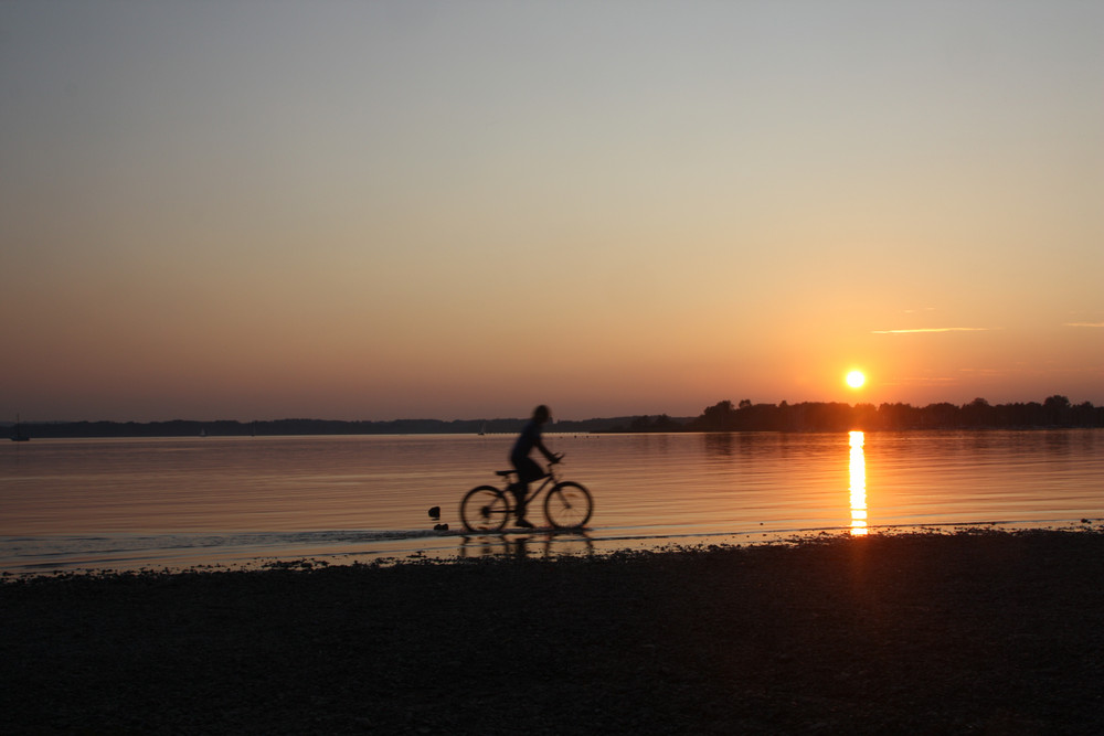 Radfahrer im Chiemsee bei Sonnenuntergang