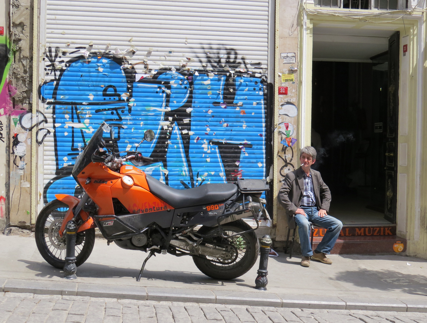 Raucher neben Motorrad vor blauem Graffiti