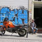 Raucher neben Motorrad vor blauem Graffiti