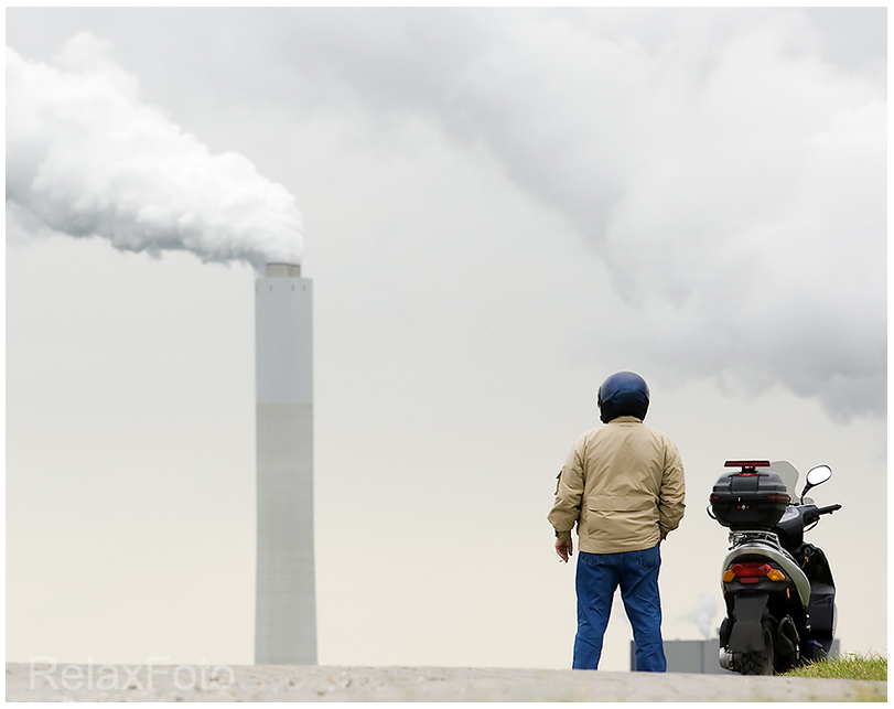 "Raucher unter sich" - Zigarette rauchender Motorrollerfahrer auf Deich vor Fabrikschornstein