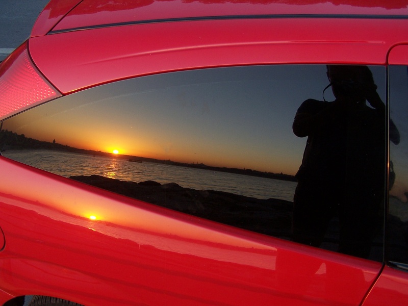 Red car and photographer in sunset.