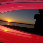 Red car and photographer in sunset.