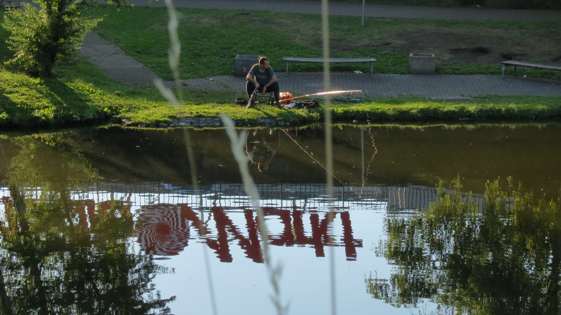 "reflektierender" Angler vor "reflektierender" Leuchtschrift