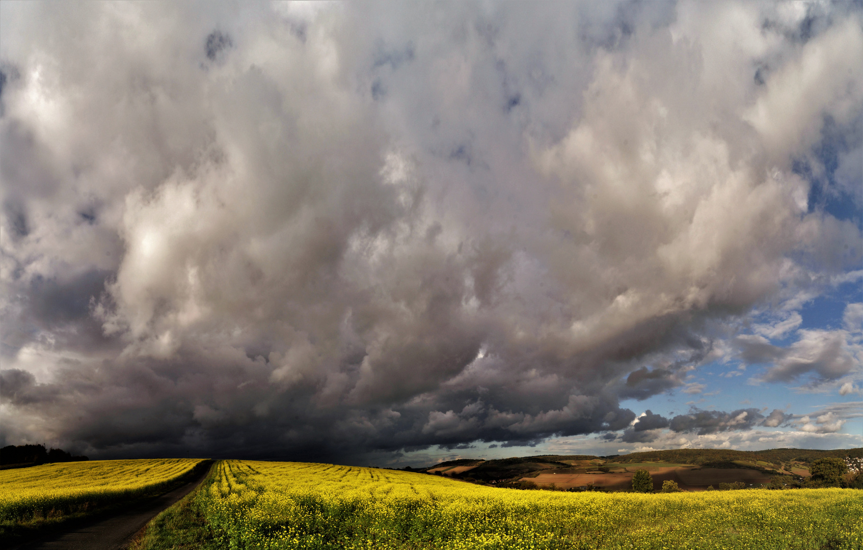 Regenwolke über dem Taubertal mit Senfblüte.