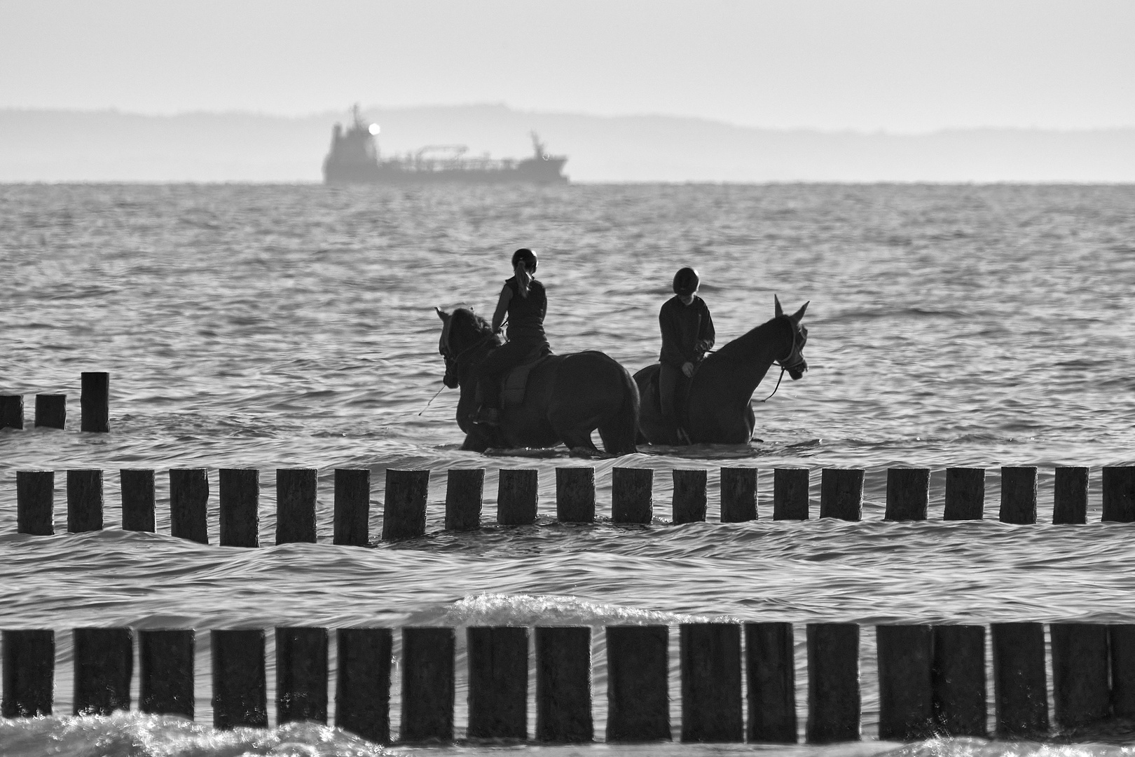 Reiterinnen in der Ostsee mit Buhnen und Schiff