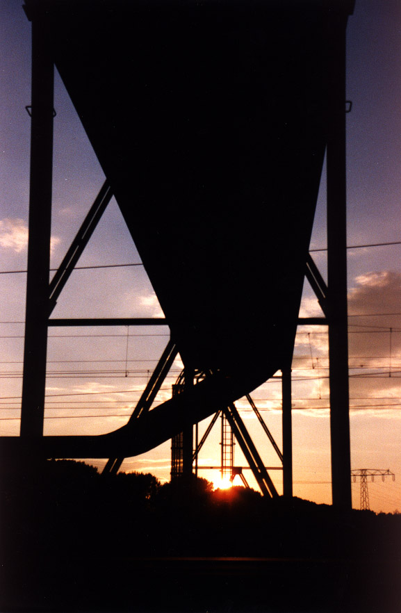 Rohrbrücke über Schienen beim Sonnenuntergang