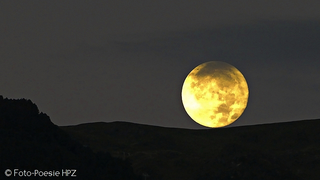 Rolling full moon on the mountain ridge...