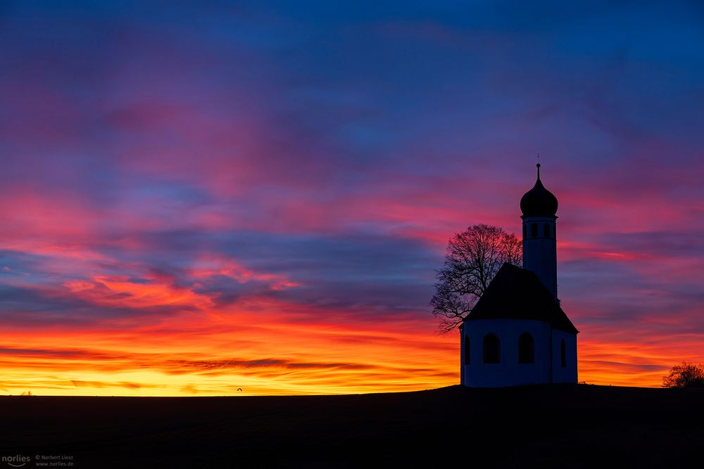 Rot leuchtende Wolken an der Kapelle