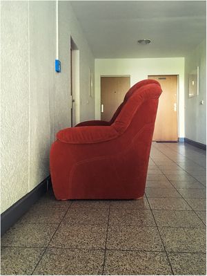 Rotes Sofa in Betrachtung eines blauen Feuermelders versunken