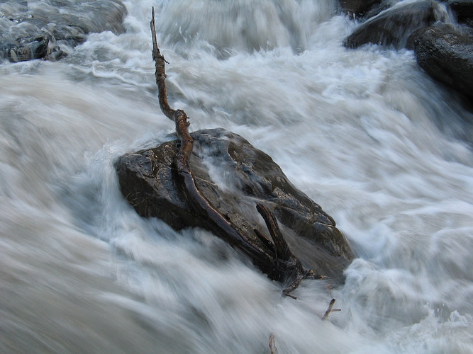 ruhender Stein in tobendem Wasser