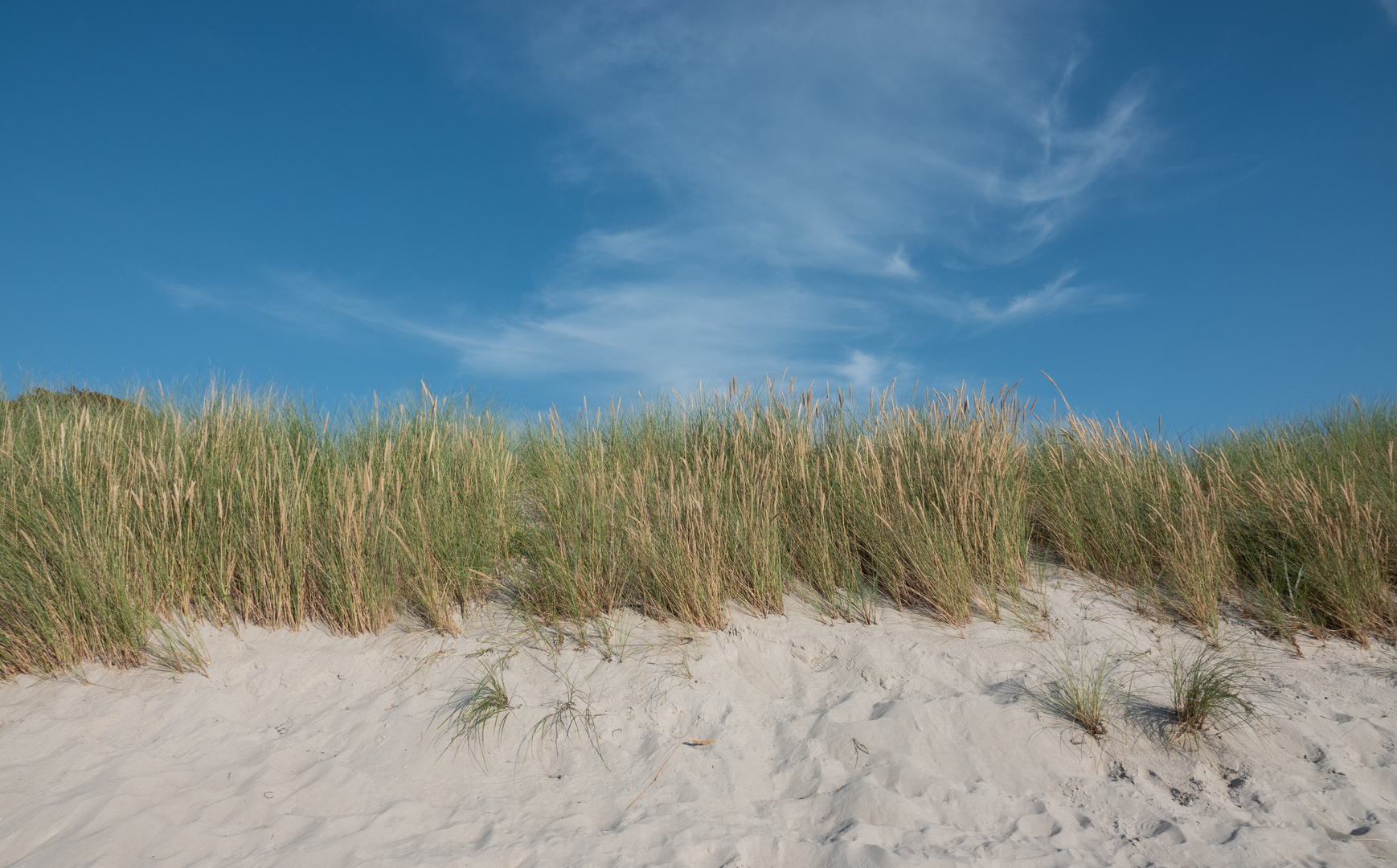 Sand, Dünen und Wolken am blauen Himmel