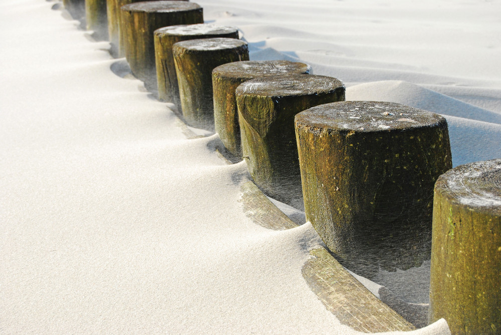 Sand weht um Holzpfähle