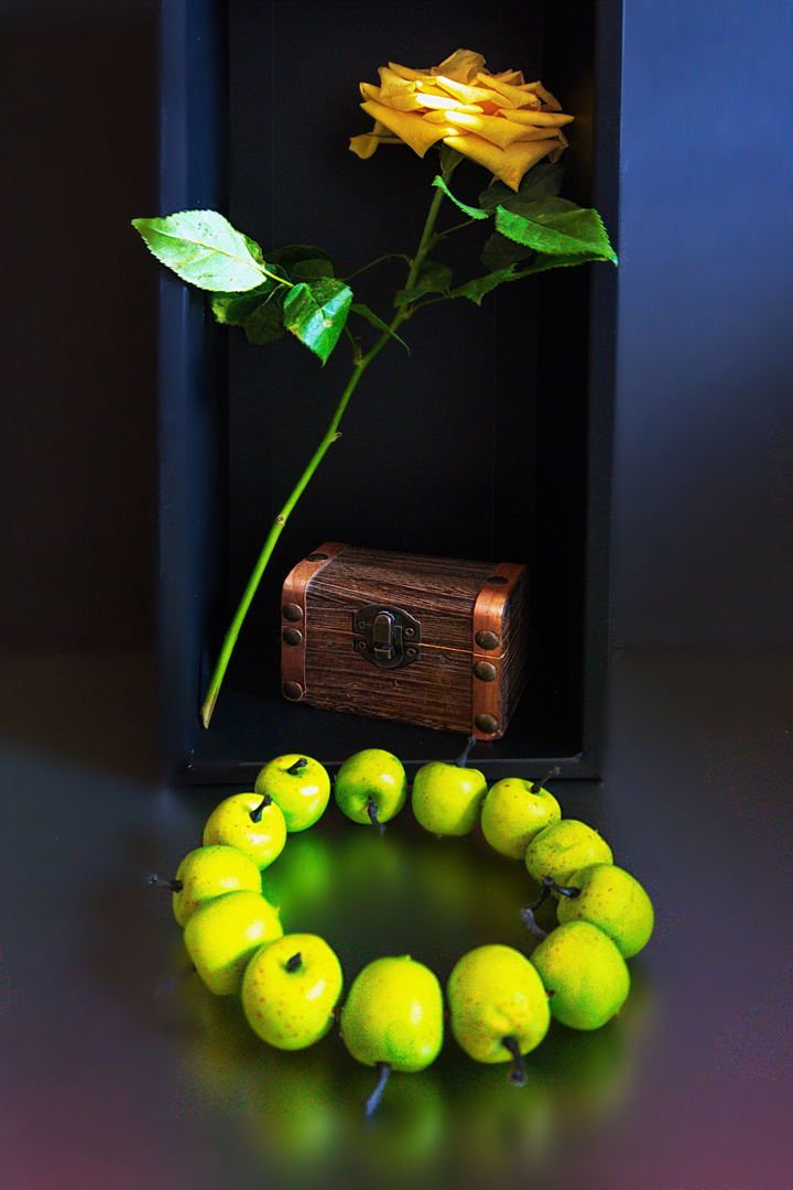 Schatztruhe mit gelber Rose und einem Ring aus grünen Äpfeln