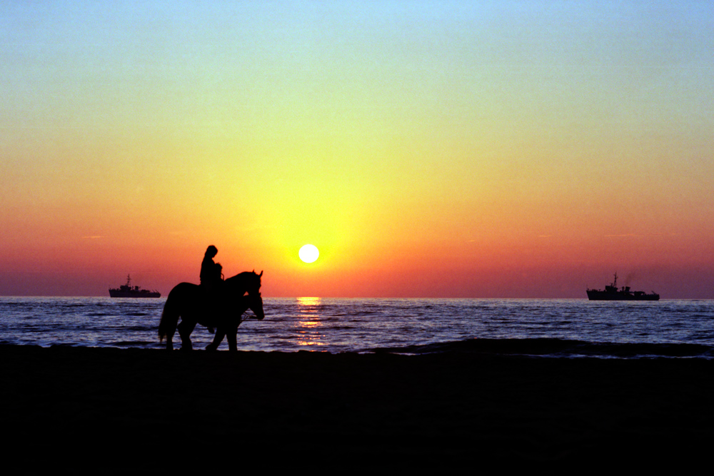 Scheveningen - Ausritt am Strand vor der Kulisse eines Marinemanövers bei Sonnenuntergang