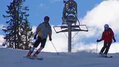 Schneekanone zwischen zwei Skifahrer