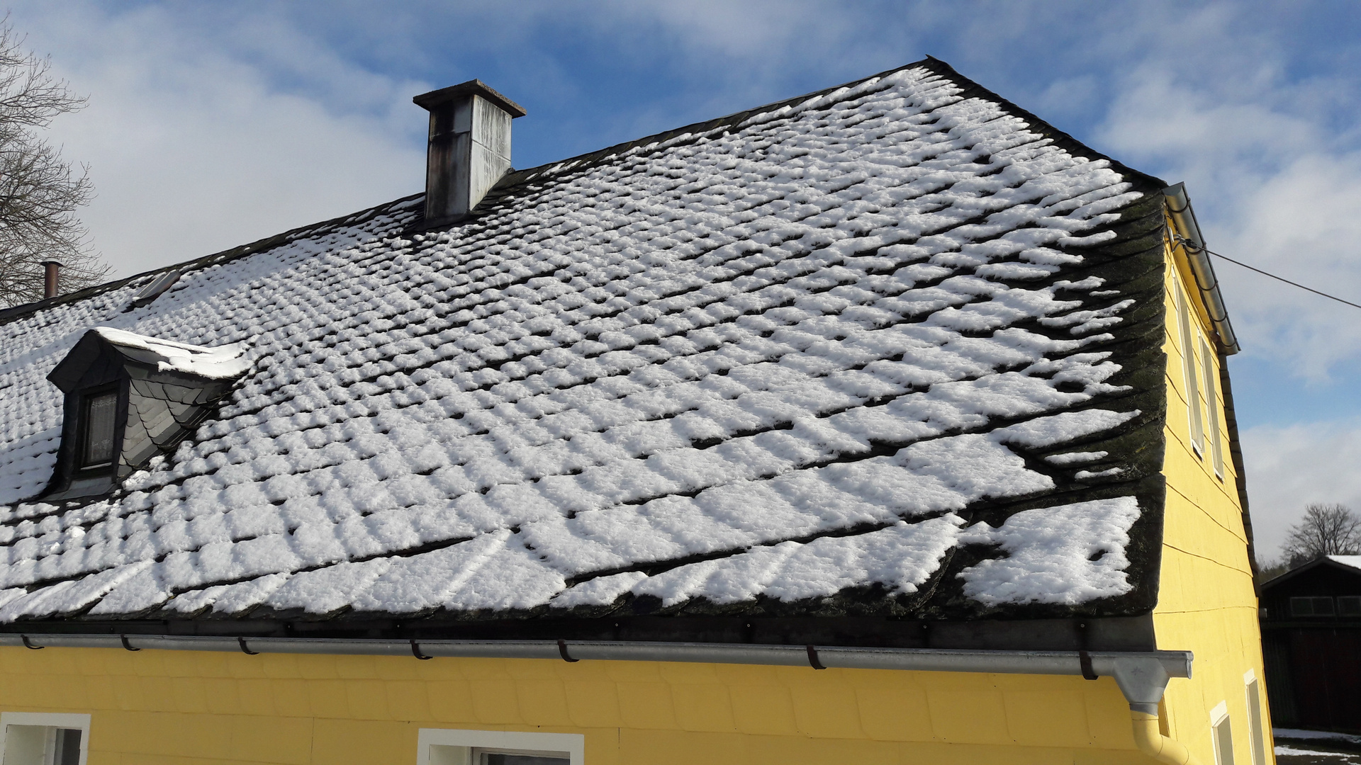 Schneemuster auf dem Naturschiefer unter blauem Himmel