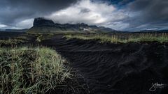 Schwarzer Sand und tiefe Wolken