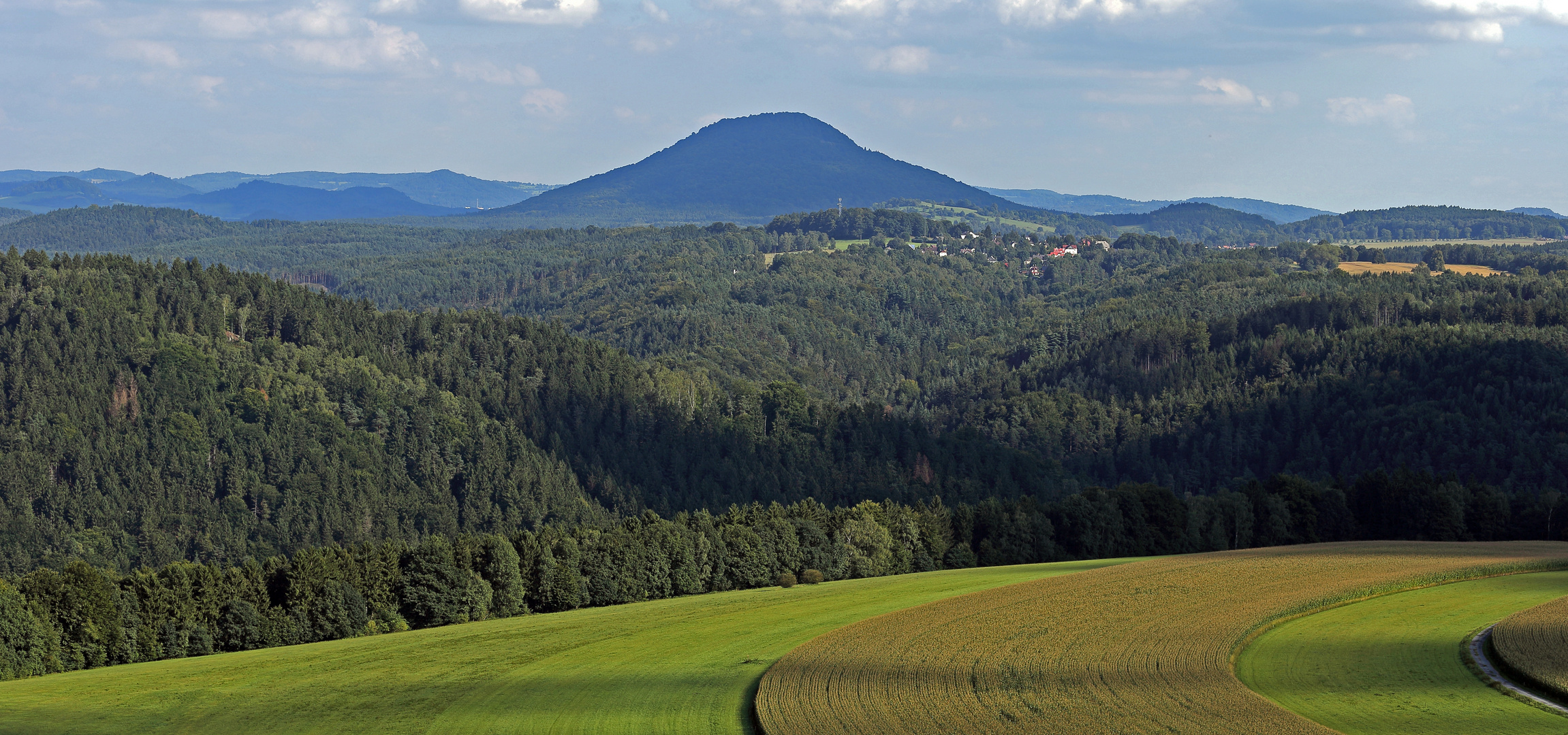 Schwungvolle Felder und Berge mit dem Rosenberg und seinen Nachbarn in Böhmen