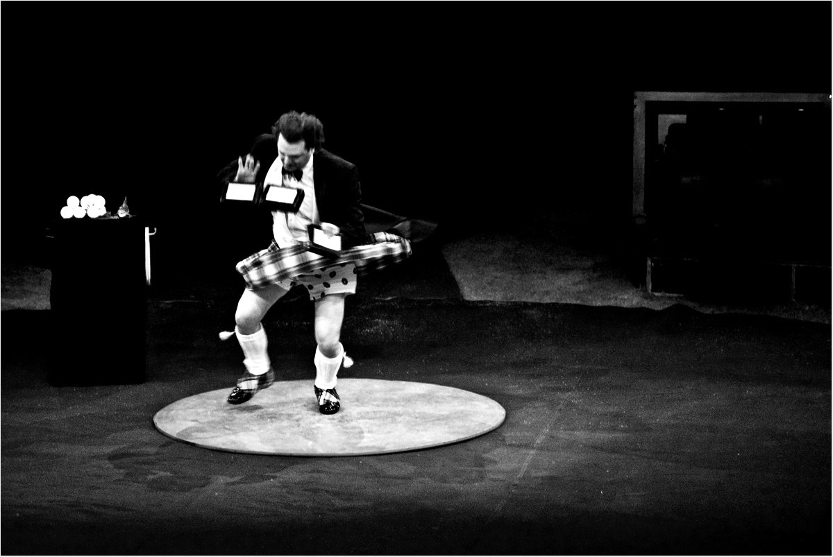 scottish juggler with tartan skirt wusching around in a circus ring