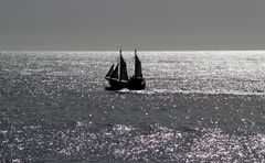 Segler auf dem durch das Abendlicht versilberten Atlantik.