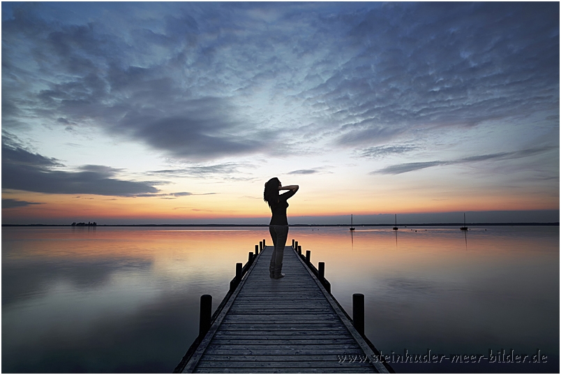 Silhouette einer Frau auf Bootssteg am Steinhuder Meer nach Sonnenuntergang