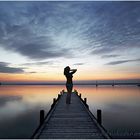 Silhouette einer Frau auf Bootssteg am Steinhuder Meer nach Sonnenuntergang