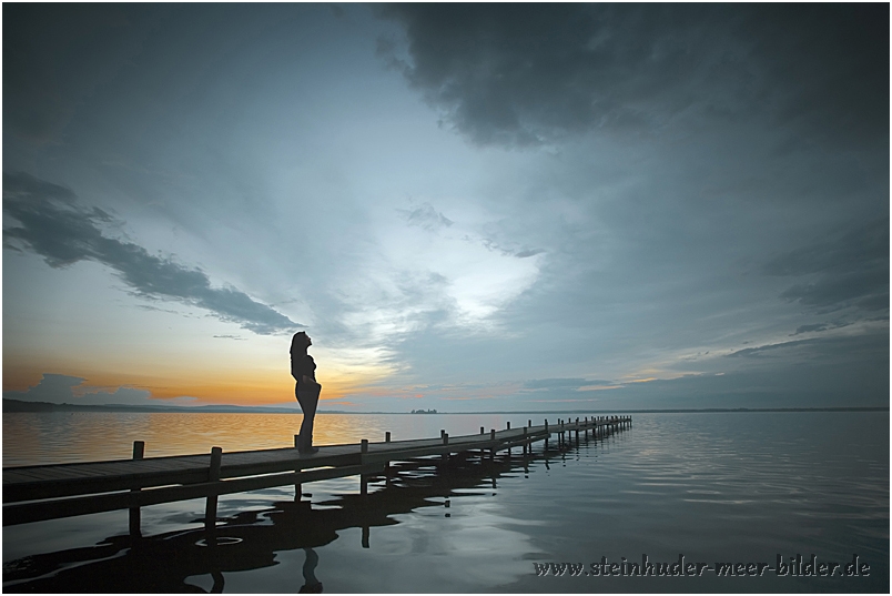 Silhouette einer Frau auf einem Steg in Steinhude mit Abendstimmung am Steinhuder Meer