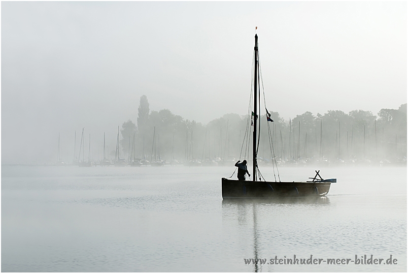 Silhouette von Fischerboot mit Fischer beim Auslaufen auf dem Steinhuder Meer im Morgennebel