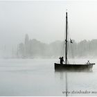 Silhouette von Fischerboot mit Fischer beim Auslaufen auf dem Steinhuder Meer im Morgennebel