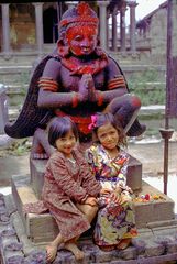 Small Newa girls in Lalitpur in front of Garuda statue