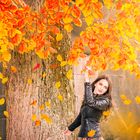 Smiling woman under a tree with falling leaves