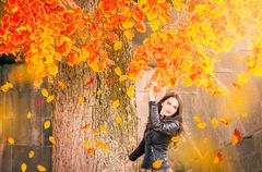 Smiling woman under a tree with falling leaves