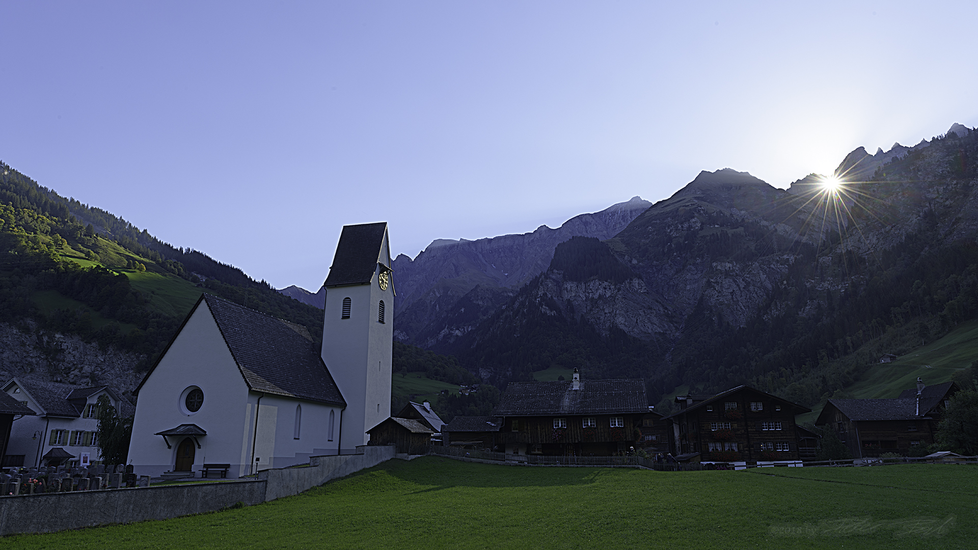 Sonne scheint durchs Martinsloch auf die Kirche von Elm